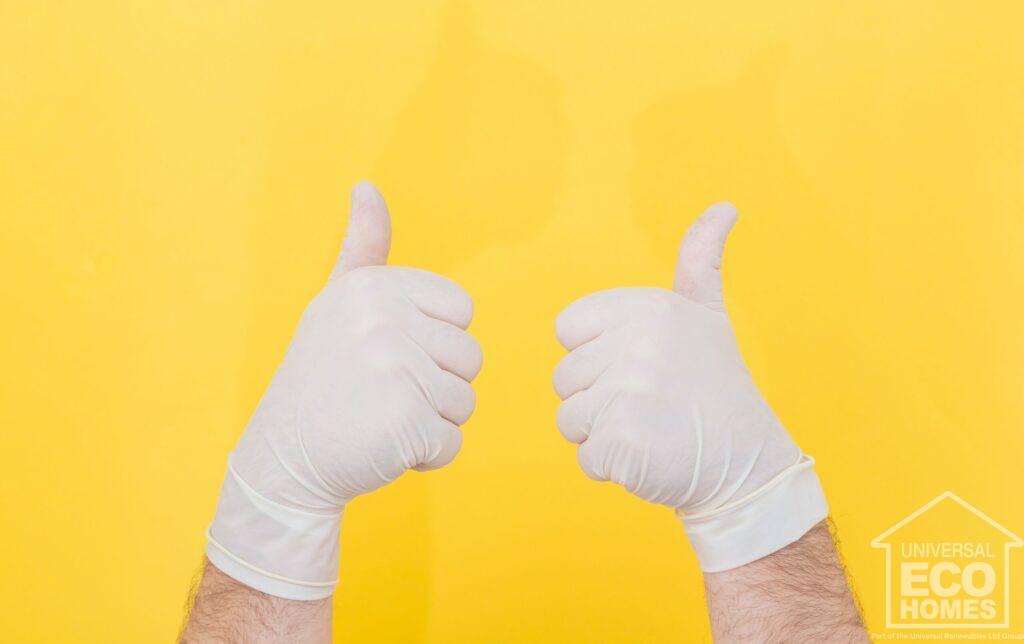 Two hands wearing white gloves giving thumbs up against a yellow background.