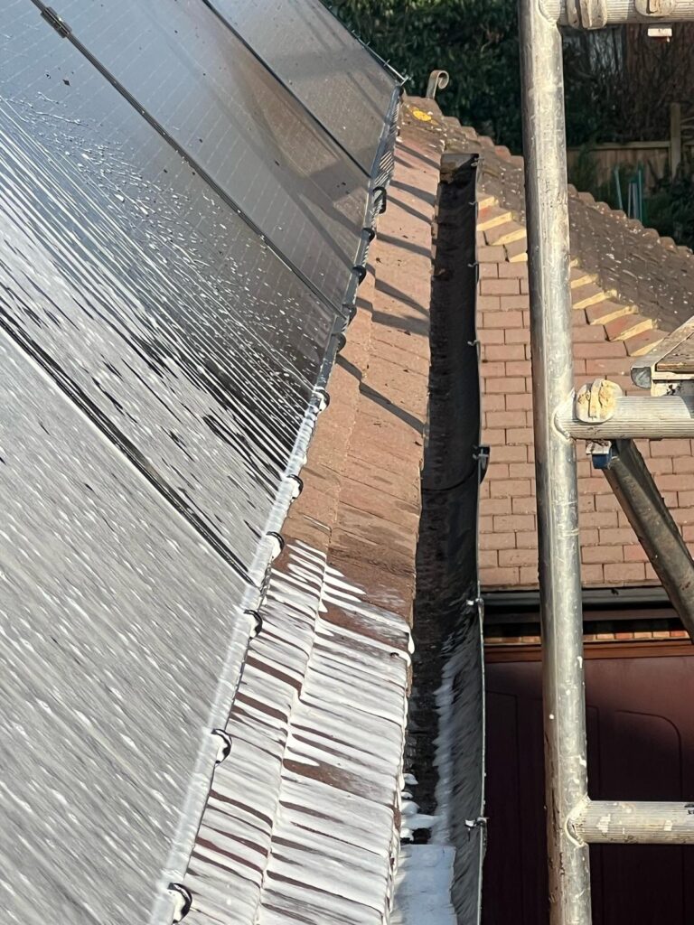 Professional team performing gutter and roof cleaning on a residential property, removing moss and debris to restore roof appearance.