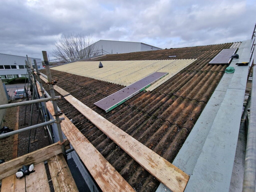 Corrugated roof of commercial building with wooden planks as walkways to be able to complete asbestos roof cleaning