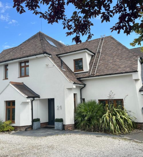Professional roof cleaners using low-pressure equipment to safely clean a large roof fitted with solar panels on a modern Nottingham home.